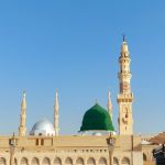 Kubah hijau dan menara Masjid Nabawi di Madinah di bawah langit biru cerah
